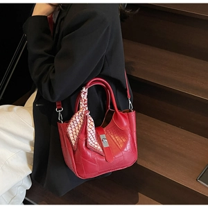 Detail of red crocodile-pattern handbag with checkered silk scarf and long strap