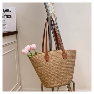 Detail of hand-woven straw bucket bag with brown leather handles and interior flower decoration