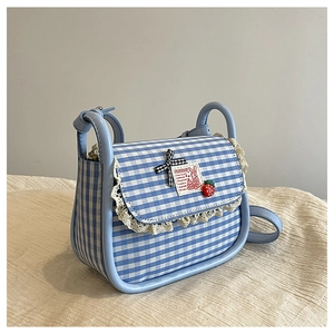 Detail of blue vichy check mini bag with lace trim, strawberry charm and bow accent