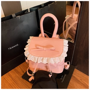Detailed macro view of pink patent leather backpack with lace trim and bow accent