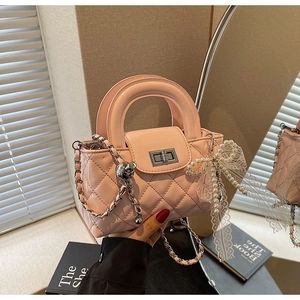 Close-up of pink quilted patent leather bag with pearl bow and lace charm detail