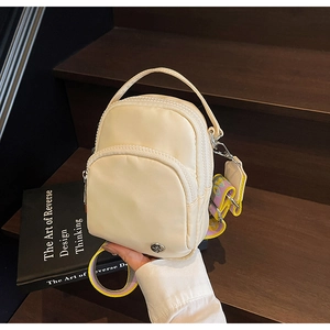 Détail d'un sac bandoulière en nylon beige avec fermetures éclair et sangle jacquard