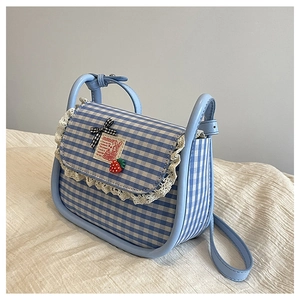 Detail of blue gingham canvas bag with lace trim, bow, and strawberry ornament