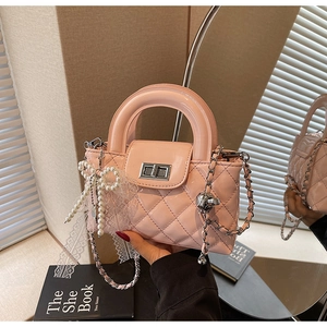 Detail of pink quilted patent leather handbag with pearl charm and metal twist lock