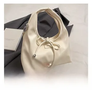 Detail showing cream bow drawstring handbag with NO FILTER label and adjustable strap