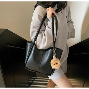 Detail of black PU leather bucket bag with lion plush charm and vertical stitching