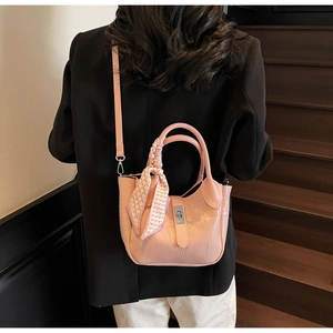 Detailed view of pink croc-embossed bucket bag with silk scarf and silver twist lock