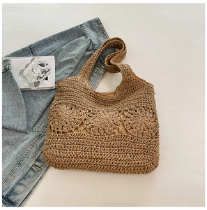 Detail of woven straw tote bag featuring intricate crochet flower patterns and textured weave