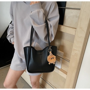 Detailed view of a black large-capacity tote bag with sleek stitching and plush charm