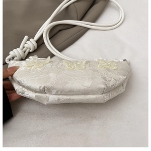 Detail der weißen Jacquard-Halbmondtasche mit Blumenmuster und feinen Schmetterling-Applikationen
