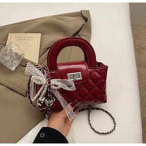 Detail of burgundy quilted leather mini bag with silver twist lock and lace bow charm