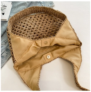 Close-up of woven straw beach bag featuring inner lining and gold magnetic snap closure