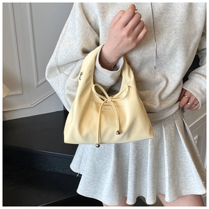 Detail of cream drawstring bucket bag with bow and NO FILTER text on soft leather