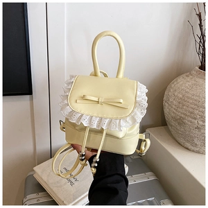 Close-up of pale yellow PU backpack with delicate white lace trim and bow detail