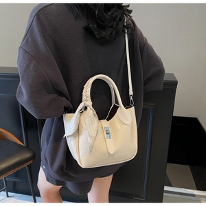 Detail of off-white crocodile embossed bucket bag with silver lock and silk scarf handle