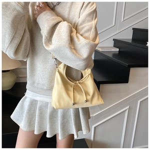 Close-up of minimalist cream hobo bag featuring silver bead drawstring detail and wide strap