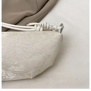 Detail aus weißem Jacquard-Stoff mit Blumenstruktur und geknotetem Seilgriff an Tasche