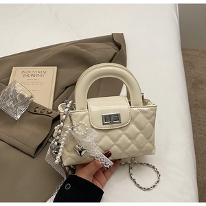 Quilted crossbody bag featuring elegant pearl lace charm and silver twist-lock closure