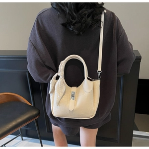 Detail of cream bucket bag with crocodile texture and silk scarf handle on shoulder