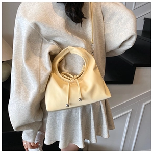 Close-up of cream PU leather handbag with circular handle and drawstring knot detail