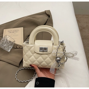 Macro detail of quilted leather texture and silver chain strap on cream handbag