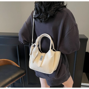 Detail of cream croc-effect bucket bag featuring a silk scarf handle and silver twist lock