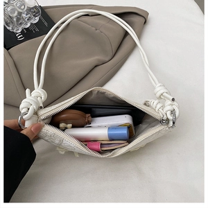 Detail der weißen Schultertasche mit geräumigem Innenraum und geknotetem Trageriemen