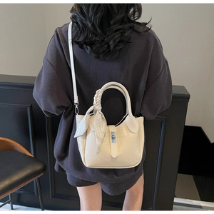 Detail of ivory faux crocodile bucket bag with silk scarf handle and silver twist lock