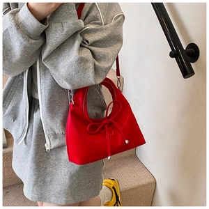 Detail of red crescent hobo bag featuring a decorative bow and silver bead accents