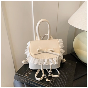 Detailed macro view of the cream mini backpack featuring delicate lace trim and bow accent