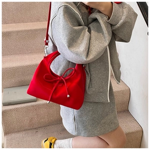 Detailed view of a red hobo bag featuring a decorative bow knot and slim shoulder strap