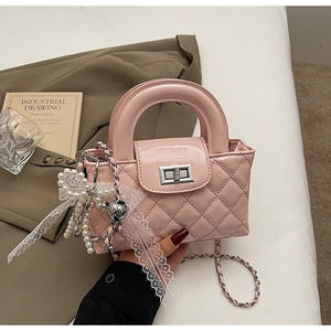 Detailed close-up of pink quilted patent leather handbag with pearl and lace charms