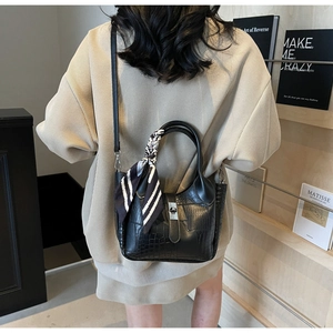 Detailed back view of black crocodile-embossed bucket bag with striped silk scarf
