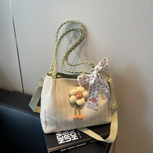 Dettaglio della borsa in paglia intrecciata con manici verdi e ciondoli a fiori