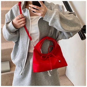 Detail of red synthetic leather handbag with knot design and silver hardware accessories