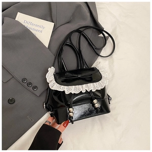 Detail of black patent leather backpack with white lace trim and bow knot detail