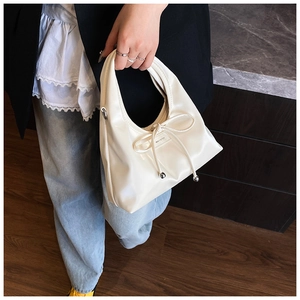 Detail of a creamy white Hobo bag with bow drawstring and NOFILTER logo for women