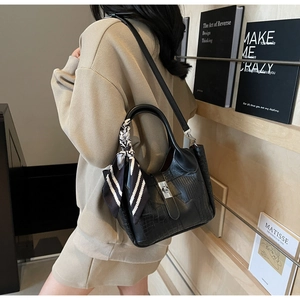 Detail of black crocodile texture handbag with striped silk scarf and silver clasp