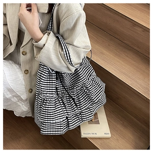 Detail of a black and white gingham tote bag with stylish ruffled layered design