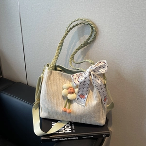 Dettaglio della borsa in paglia con manico verde e pendente floreale decorativo unico