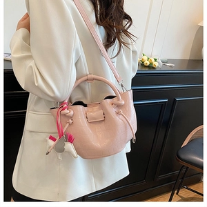 Close-up of pink faux leather handbag with crocodile pattern and white pegasus charm
