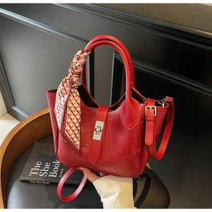 Detail of red croc-embossed bucket bag with silk scarf handle on black chair