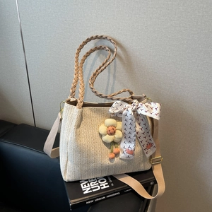 Dettaglio borsa tote in paglia con fiore in maglia e foulard di seta decorativo estate