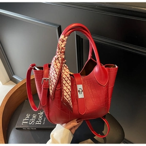 Detailed view of red crocodile textured bucket bag with decorative silk scarf and silver lock
