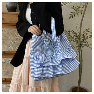 Detail of blue and white gingham tote bag with ruffled edges and drawstring closure