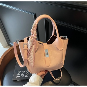 Detail of light pink crocodile pattern handbag with silver clasp and silk scarf handle