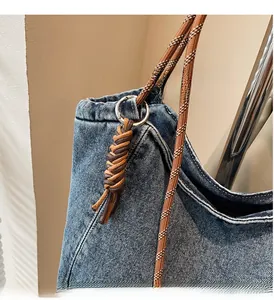 Detail of blue denim tote bag with thick woven rope strap and silver metal hardware