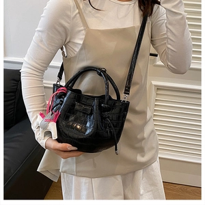 Detailed view of a black crocodile pattern bucket bag with a colorful pony charm accessory