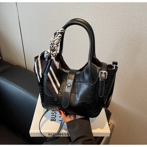 Detail showing black croc-effect paneled handbag with silver twist lock and striped scarf