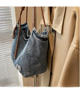 Detail of blue denim tote bag featuring rustic rope handles and vintage washed texture